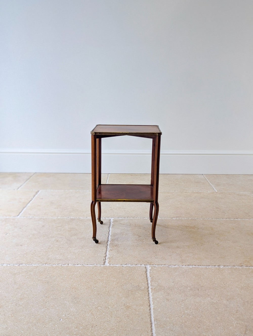 A late Victorian square mahogany two-tier occasional table with cabriole legs, brass-edged rims, and brass castors. View IV