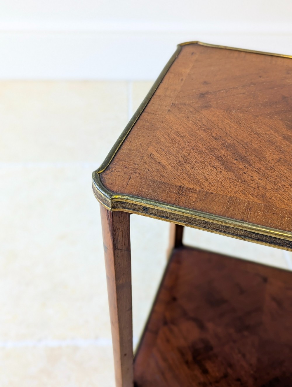 A late Victorian square mahogany two-tier occasional table with cabriole legs, brass-edged rims, and brass castors. View VI