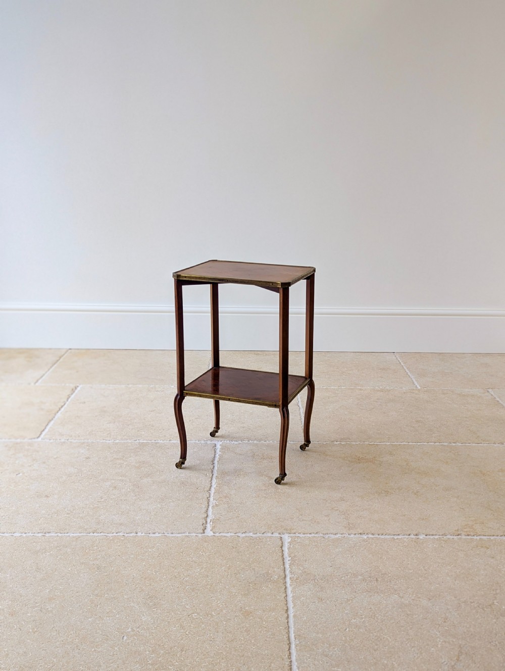 A late Victorian square mahogany two-tier occasional table with cabriole legs, brass-edged rims, and brass castors. View VIII