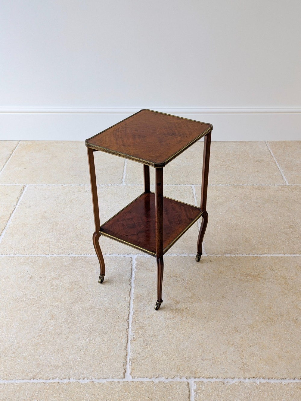 A late Victorian square mahogany two-tier occasional table with cabriole legs, brass-edged rims, and brass castors. View XI
