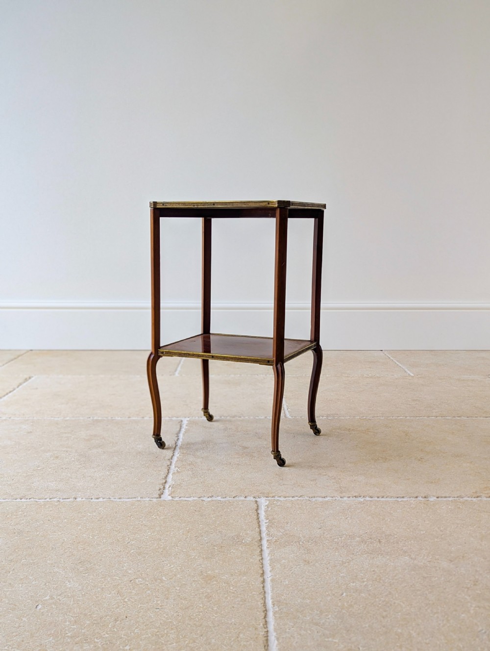 A late Victorian square mahogany two-tier occasional table with cabriole legs, brass-edged rims, and brass castors. View XII