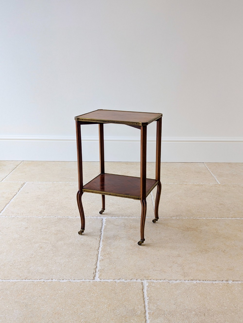 A late Victorian square mahogany two-tier occasional table with cabriole legs, brass-edged rims, and brass castors. View XIV