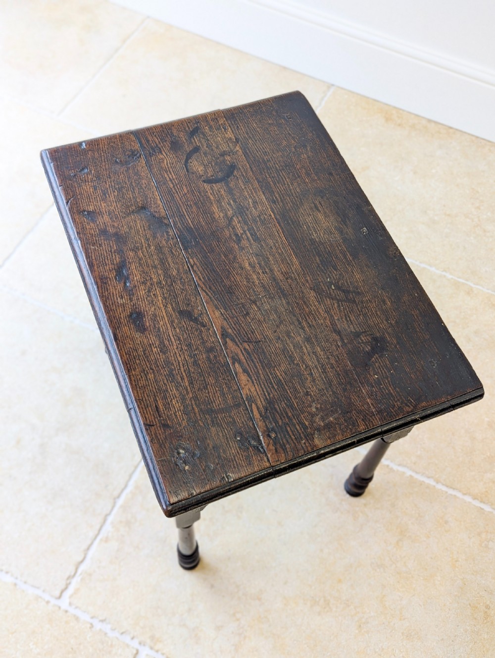 A dark oak Georgian lowboy featuring a single drawer with a brass drop handle, shaped frieze, and turned legs. View III