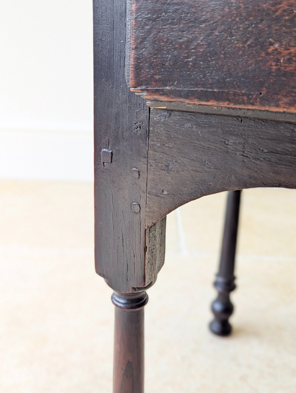 A dark oak Georgian lowboy featuring a single drawer with a brass drop handle, shaped frieze, and turned legs. View XIV
