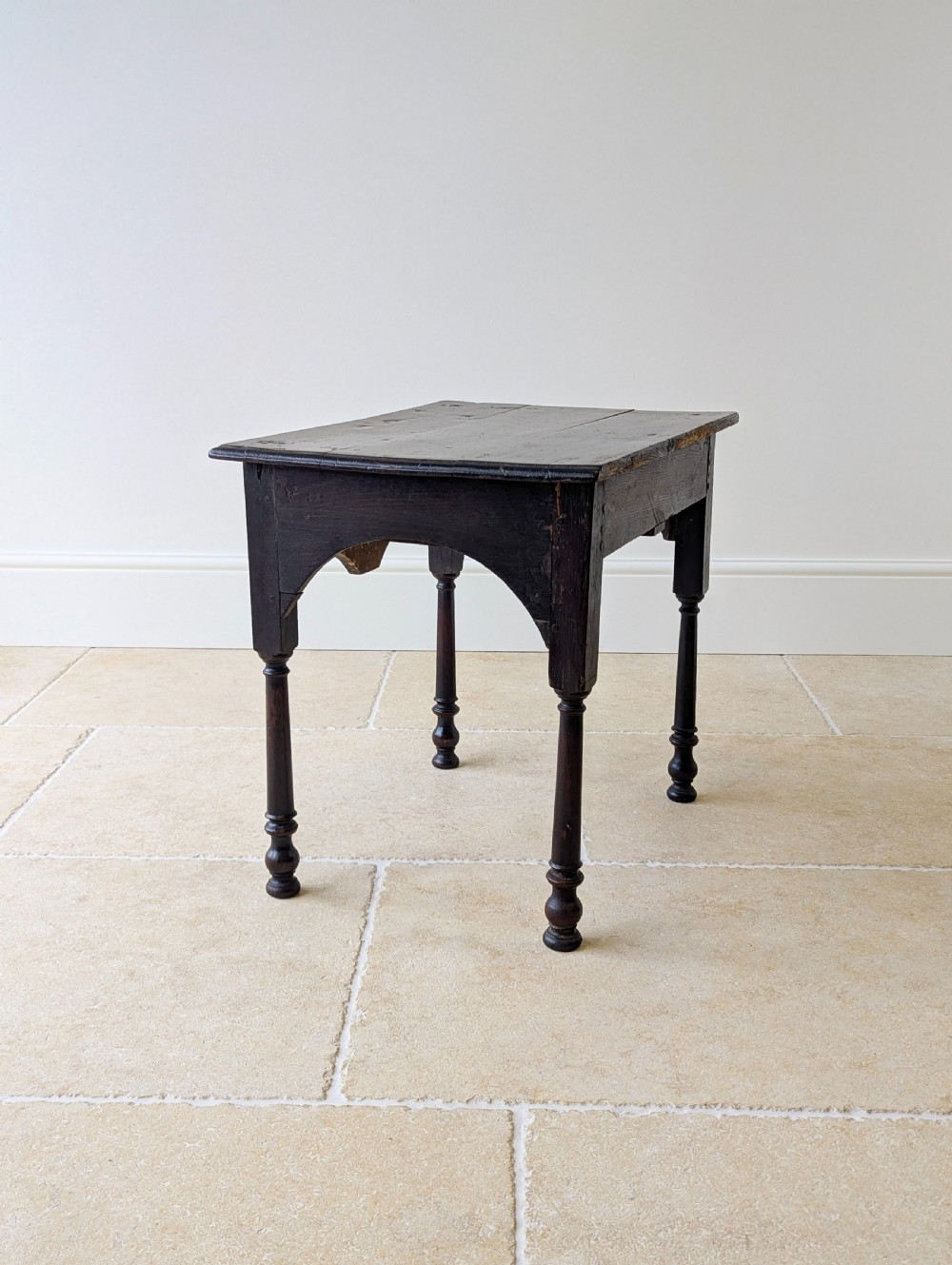 A dark oak Georgian lowboy featuring a single drawer with a brass drop handle, shaped frieze, and turned legs. View XVII