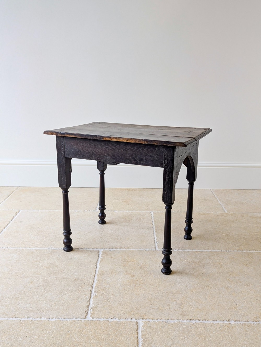 A dark oak Georgian lowboy featuring a single drawer with a brass drop handle, shaped frieze, and turned legs. View XVIII