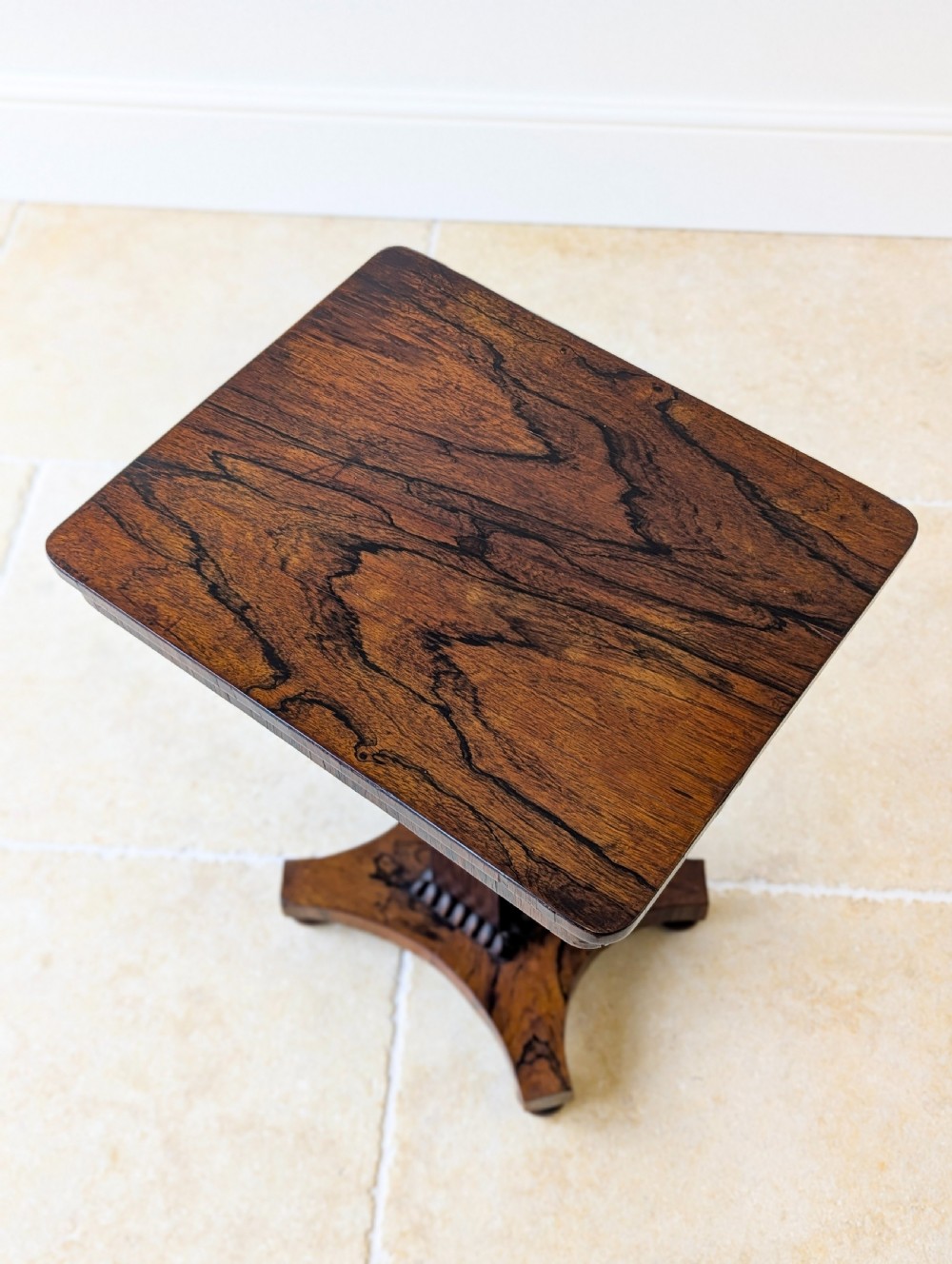 A Regency rosewood occasional table with a rectangular top, square column pedestal, and quadform base on compressed feet. View II