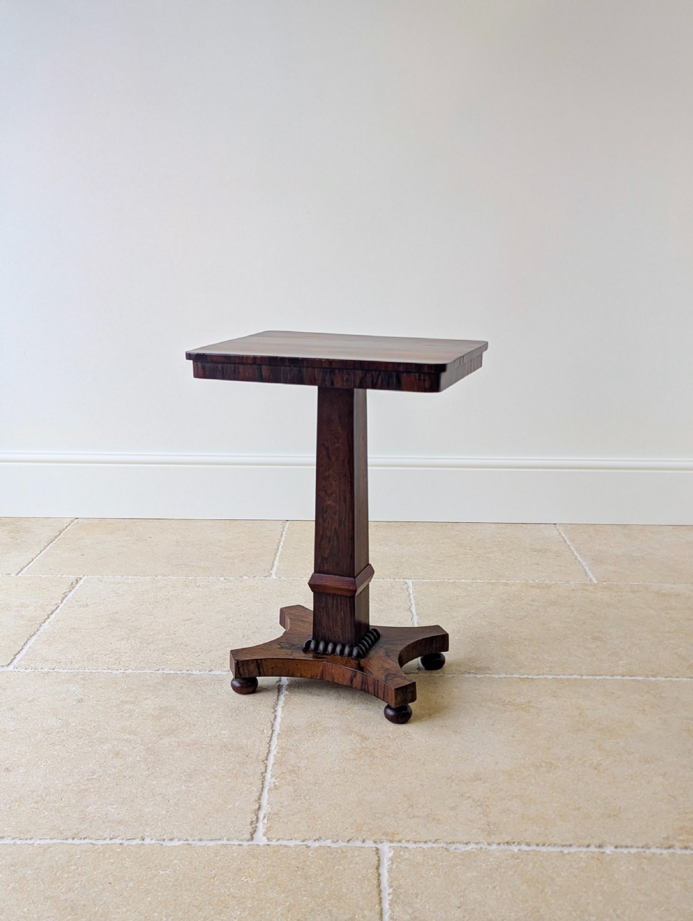 A Regency rosewood occasional table with a rectangular top, square column pedestal, and quadform base on compressed feet. View III