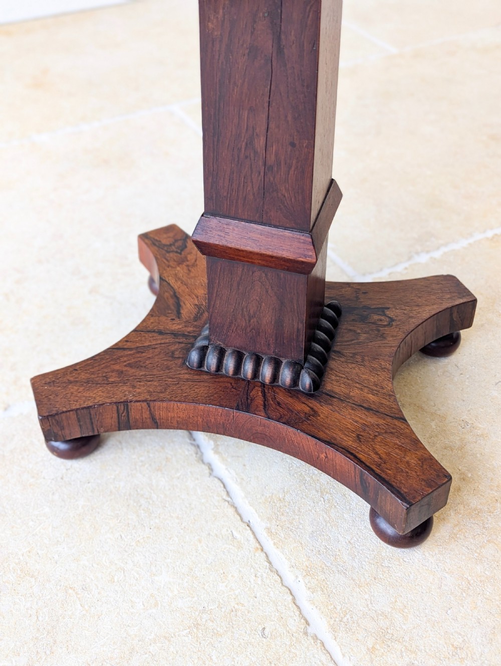 A Regency rosewood occasional table with a rectangular top, square column pedestal, and quadform base on compressed feet. View IV