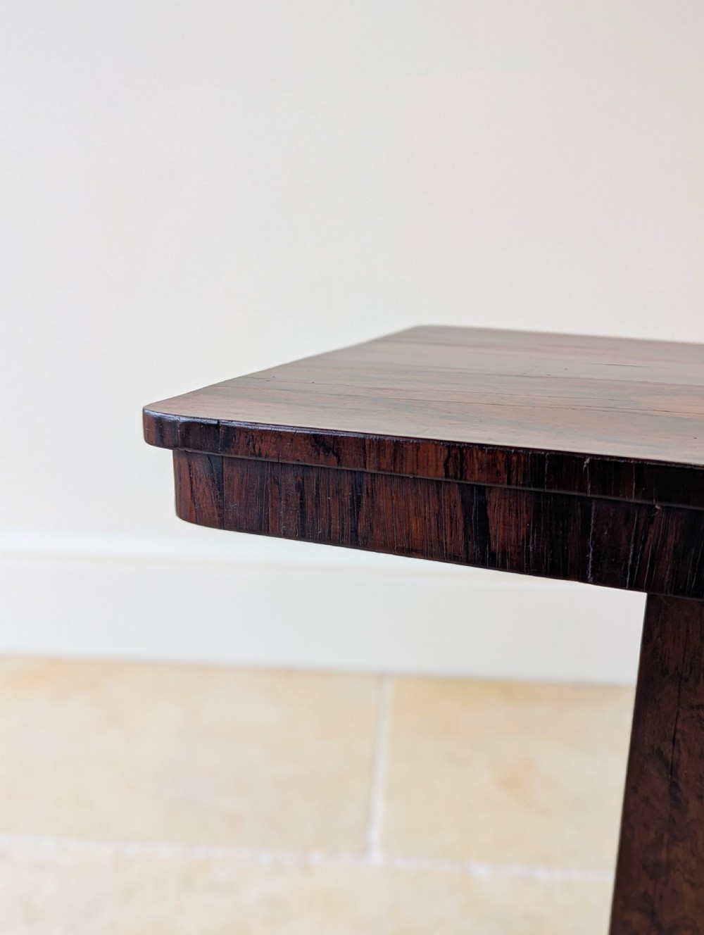 A Regency rosewood occasional table with a rectangular top, square column pedestal, and quadform base on compressed feet. View VI
