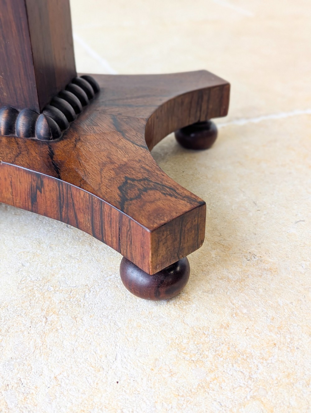 A Regency rosewood occasional table with a rectangular top, square column pedestal, and quadform base on compressed feet. View VIII
