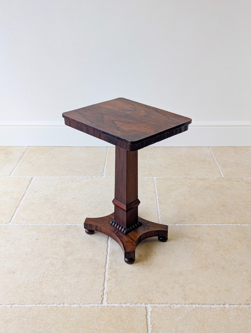 A Regency rosewood occasional table with a rectangular top, square column pedestal, and quadform base on compressed feet. View IX