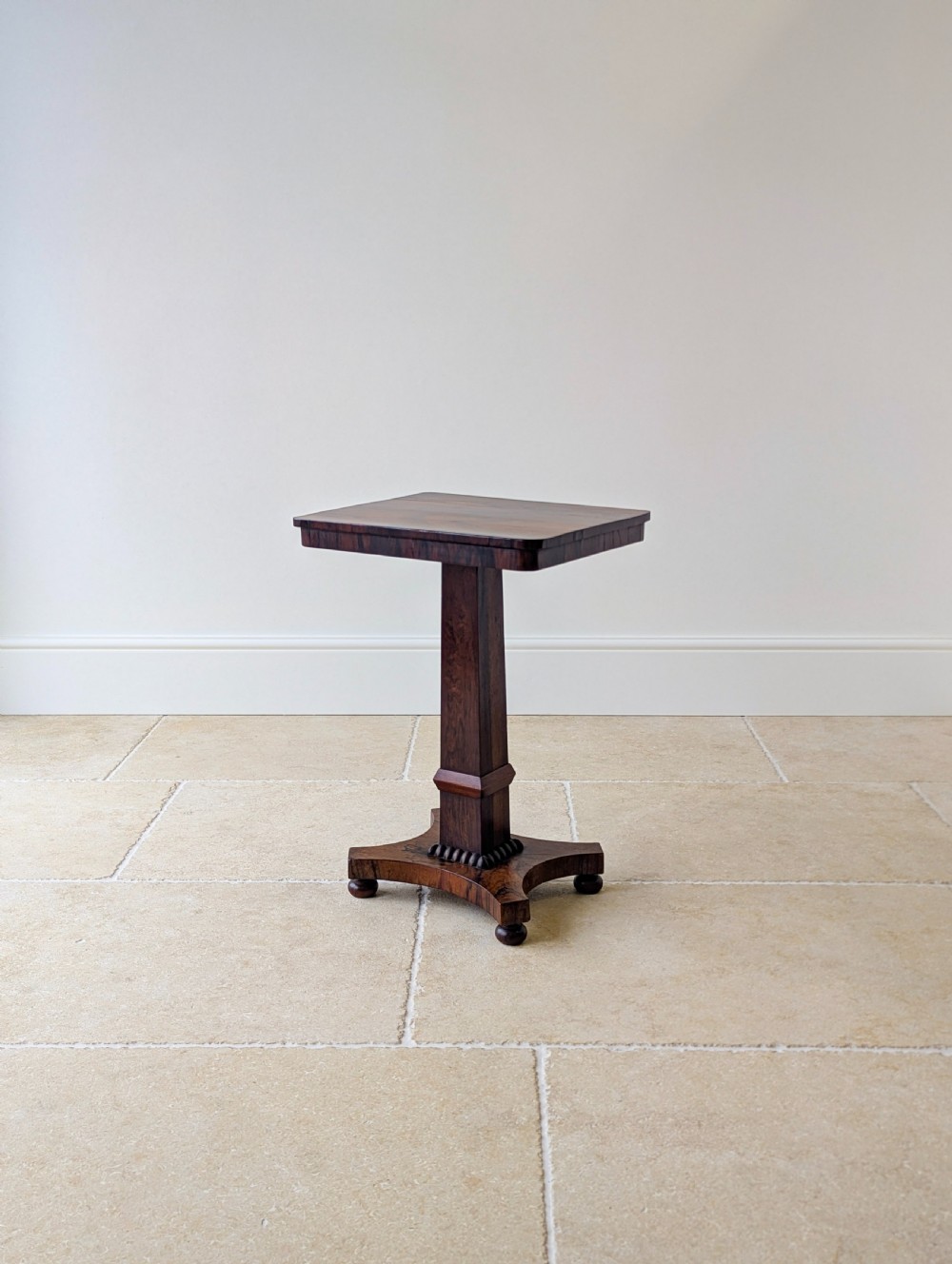 A Regency rosewood occasional table with a rectangular top, square column pedestal, and quadform base on compressed feet. View XIII