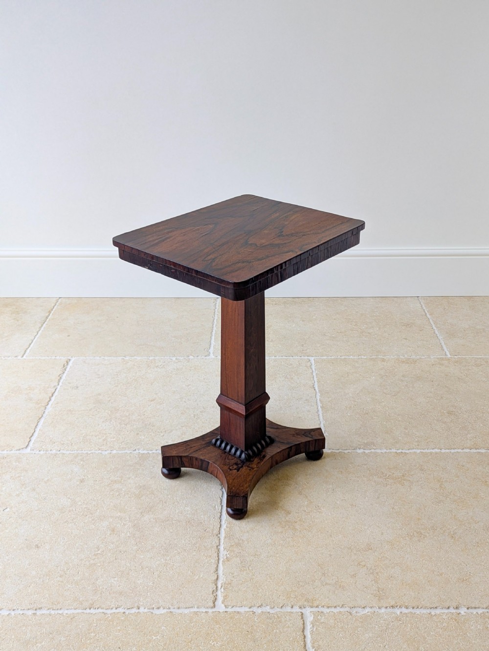 A Regency rosewood occasional table with a rectangular top, square column pedestal, and quadform base on compressed feet. View XIV