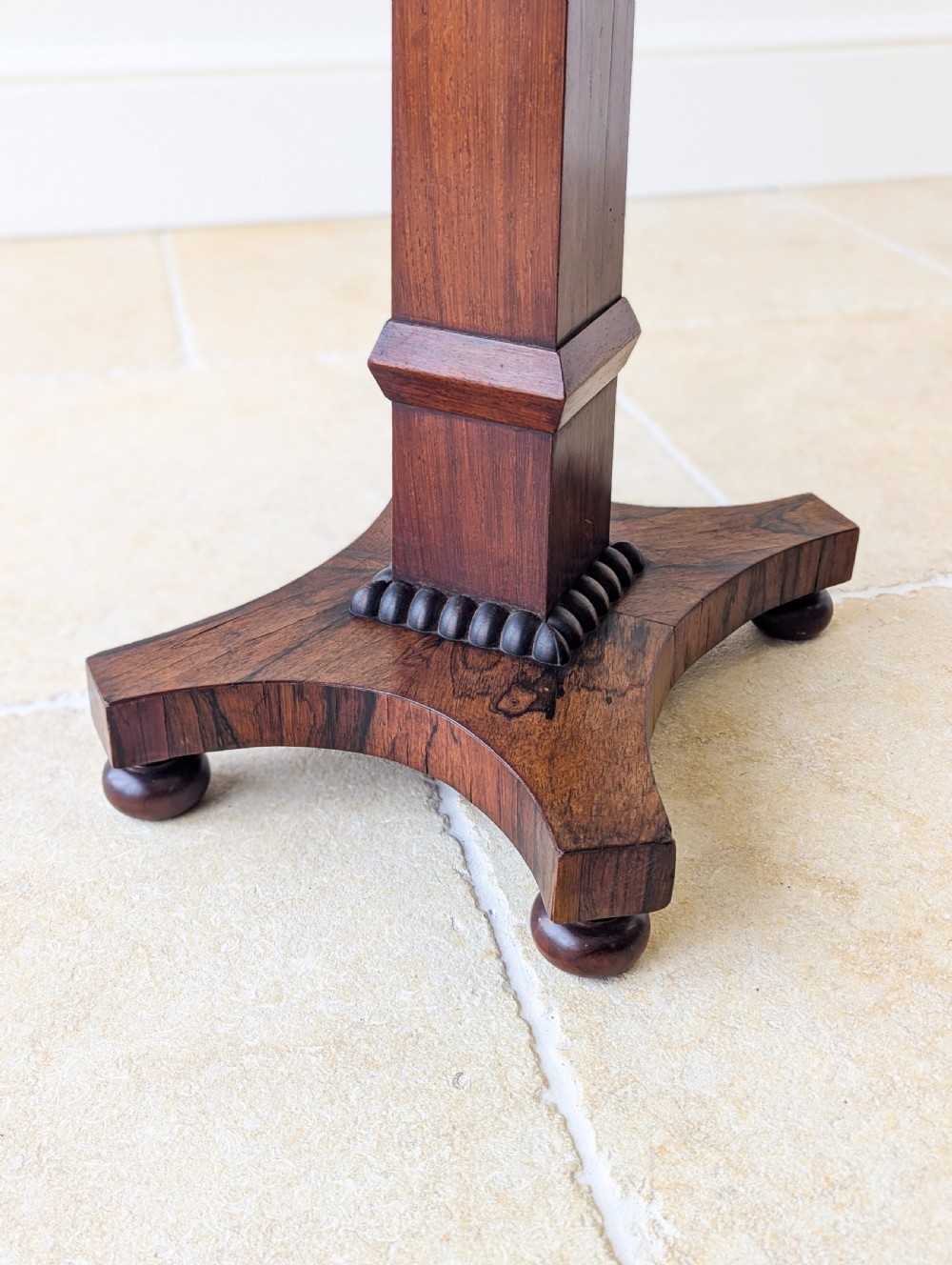 A Regency rosewood occasional table with a rectangular top, square column pedestal, and quadform base on compressed feet. View XV
