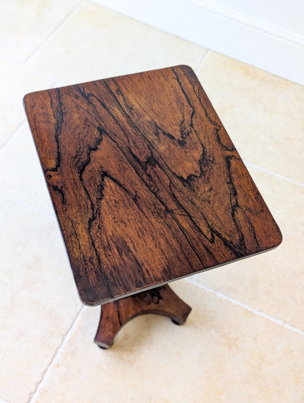 A Regency rosewood occasional table with a rectangular top, square column pedestal, and quadform base on compressed feet. View XVII