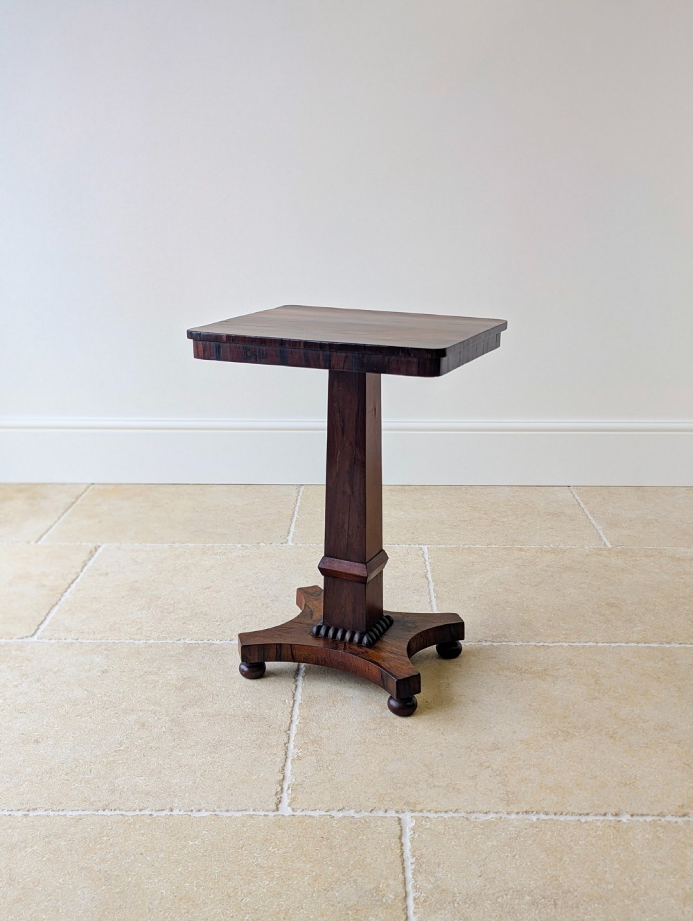 A Regency rosewood occasional table with a rectangular top, square column pedestal, and quadform base on compressed feet. View XVIII