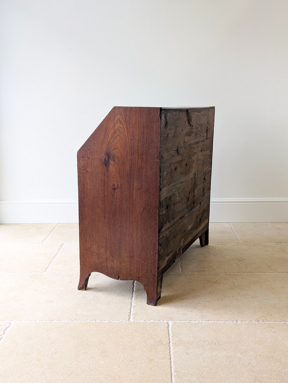 An antique Georgian mahogany slant-front bureau featuring four graduated long drawers with brass oval drop handles and shaped bracket feet. View XIX