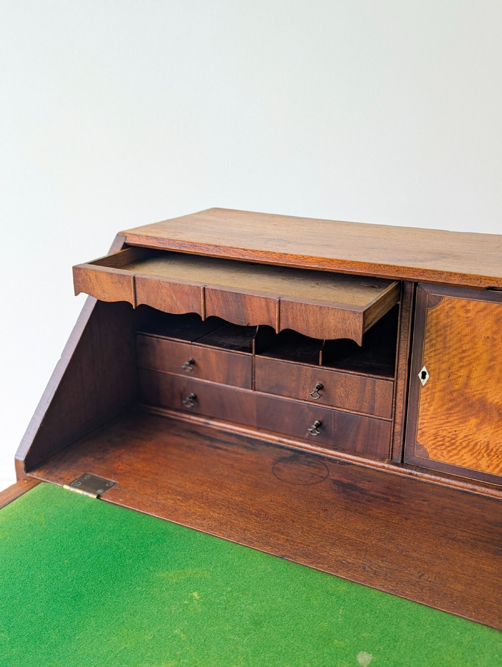 An antique Georgian mahogany slant-front bureau featuring four graduated long drawers with brass oval drop handles and shaped bracket feet. View IX