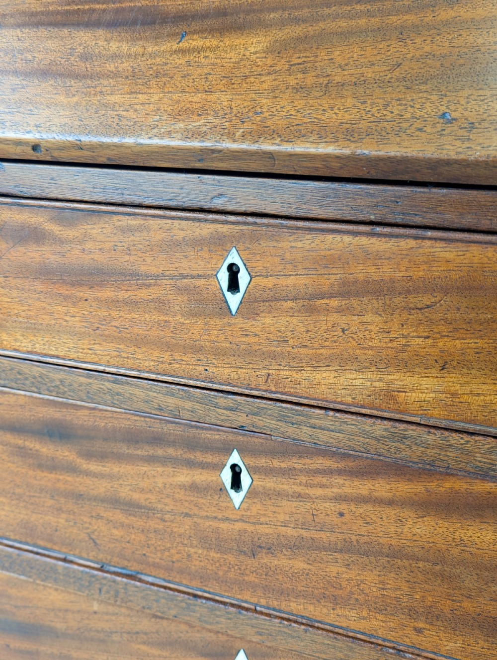 An antique Georgian mahogany slant-front bureau featuring four graduated long drawers with brass oval drop handles and shaped bracket feet. View XIII