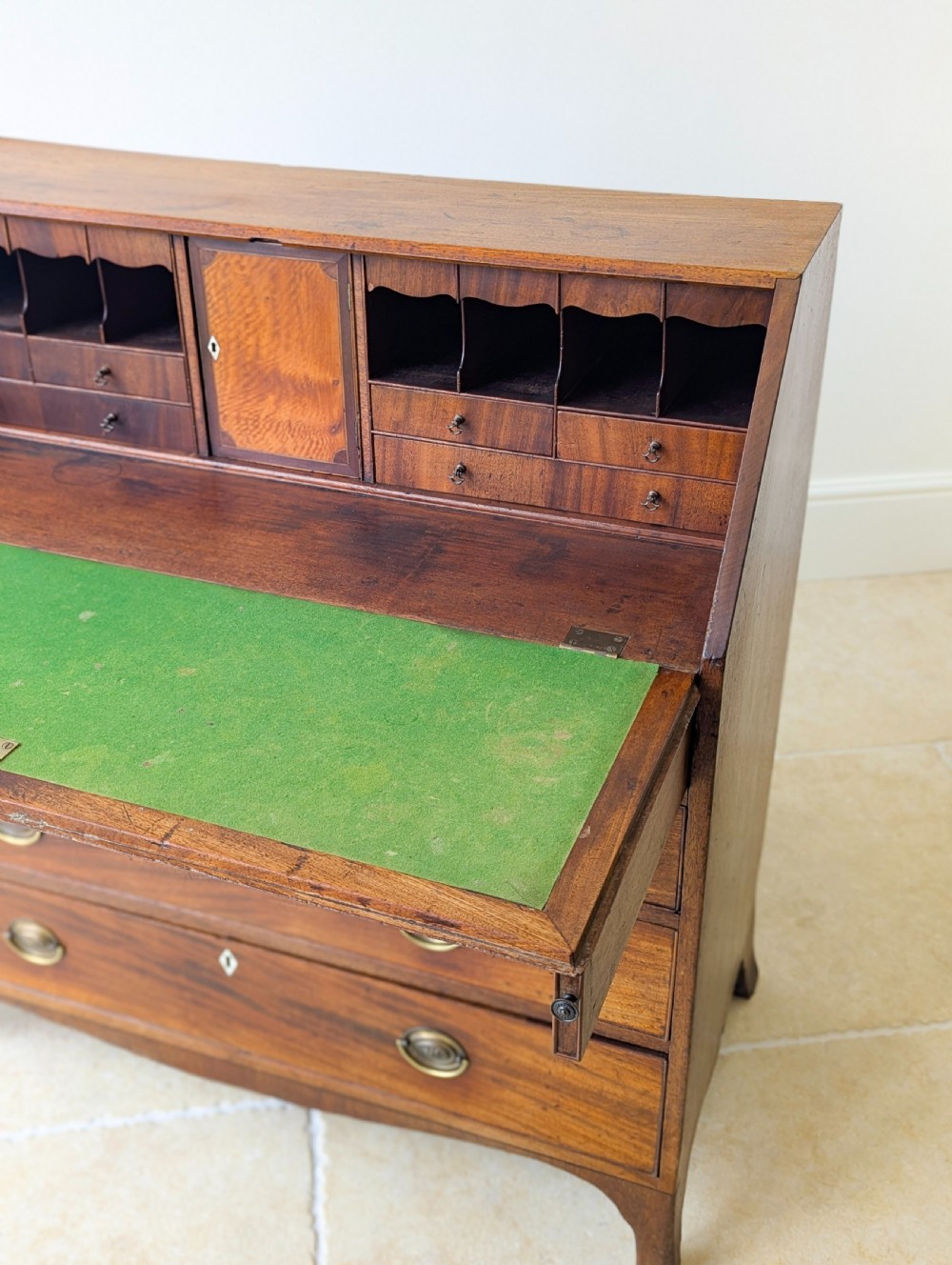 An antique Georgian mahogany slant-front bureau featuring four graduated long drawers with brass oval drop handles and shaped bracket feet. View XIV