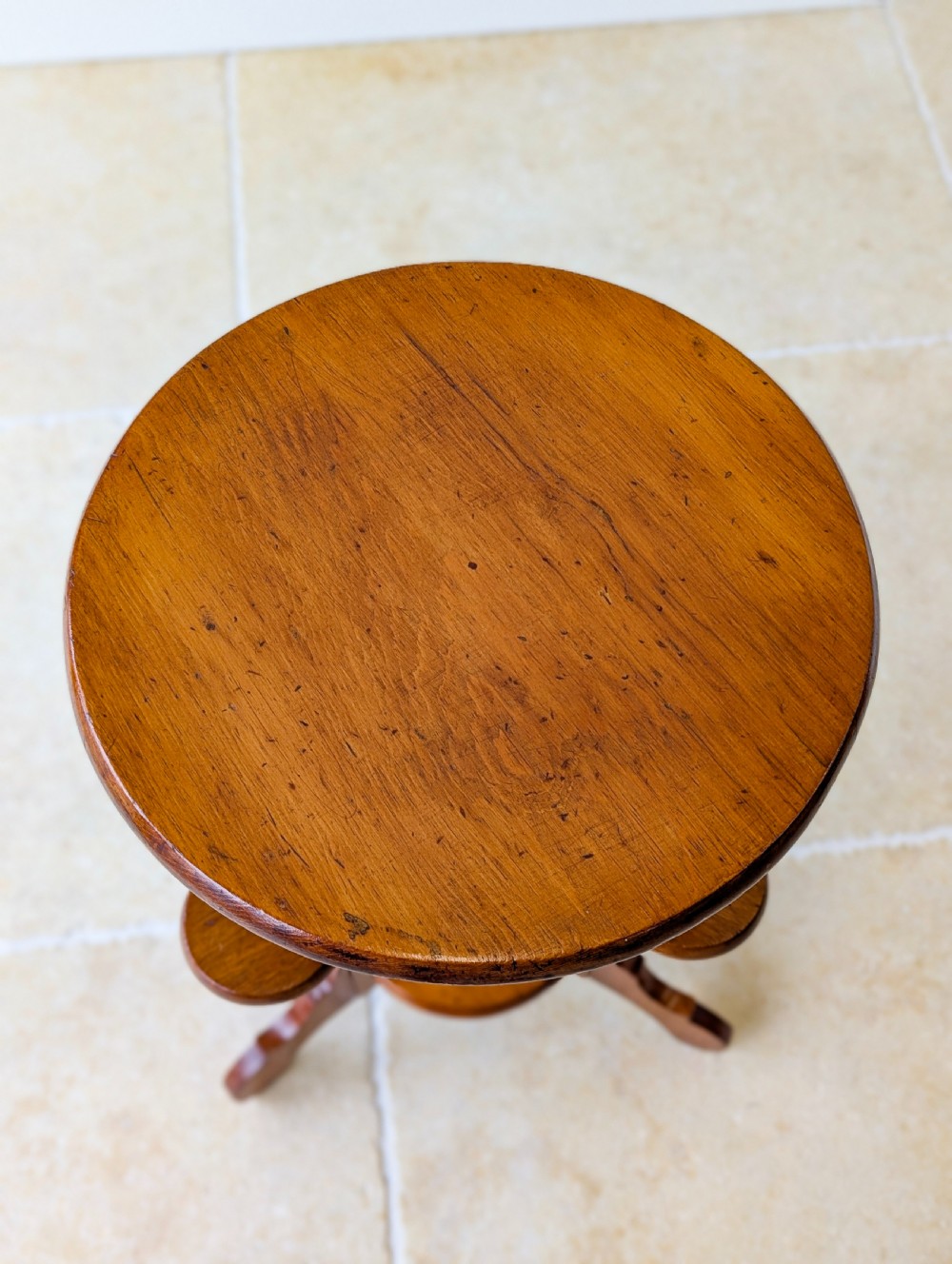 An early 20th-century stained beech occasional table featuring a circular top, three small side tiers, a lower circular shelf, and curved bracket feet. View II