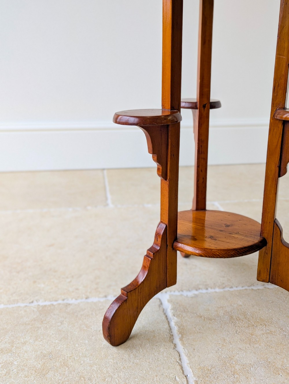 An early 20th-century stained beech occasional table featuring a circular top, three small side tiers, a lower circular shelf, and curved bracket feet. View IV
