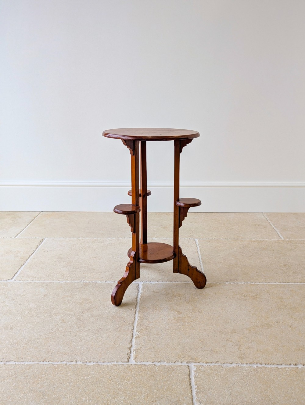 An early 20th-century stained beech occasional table featuring a circular top, three small side tiers, a lower circular shelf, and curved bracket feet. View VI