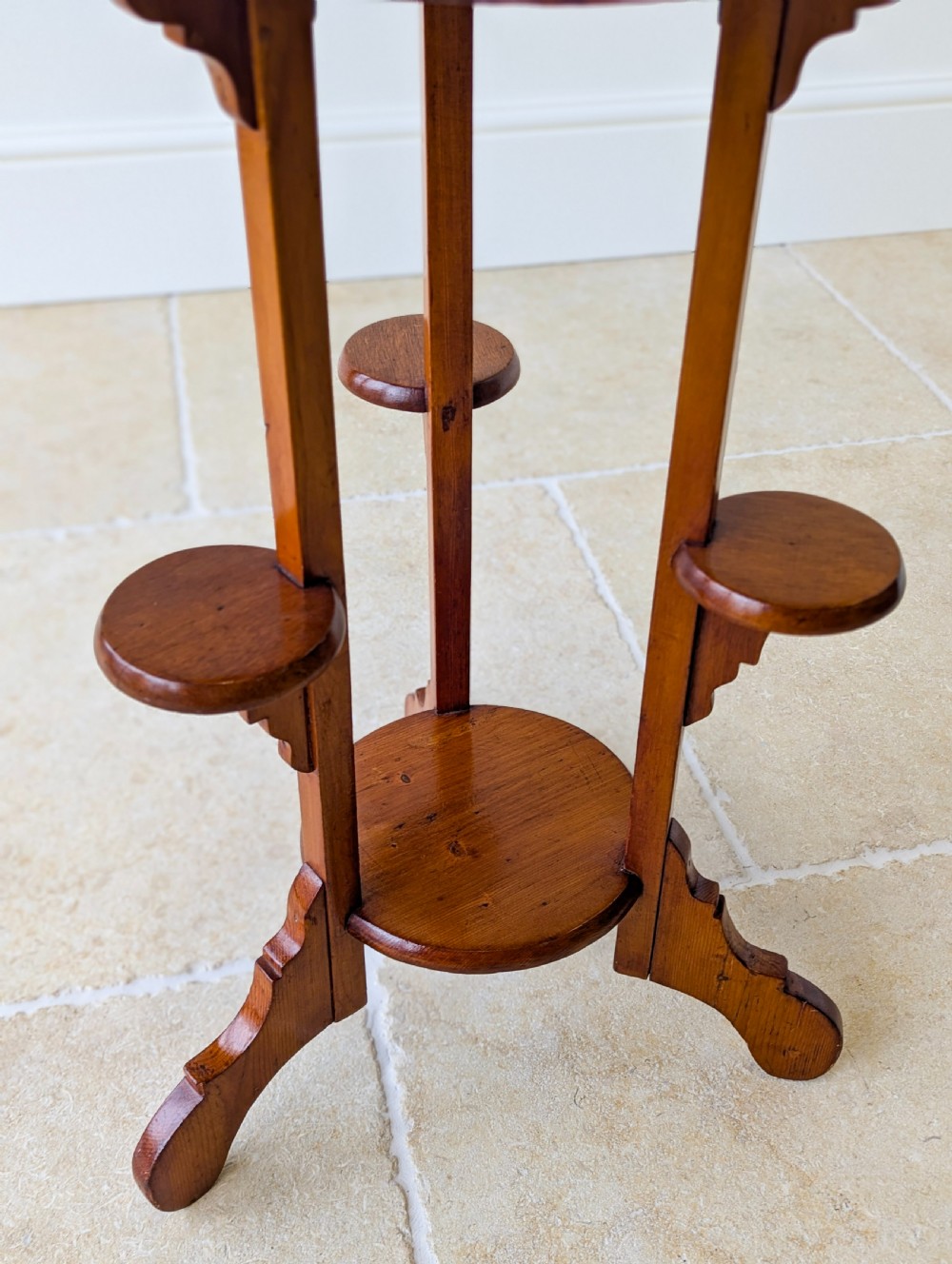 An early 20th-century stained beech occasional table featuring a circular top, three small side tiers, a lower circular shelf, and curved bracket feet. View VII