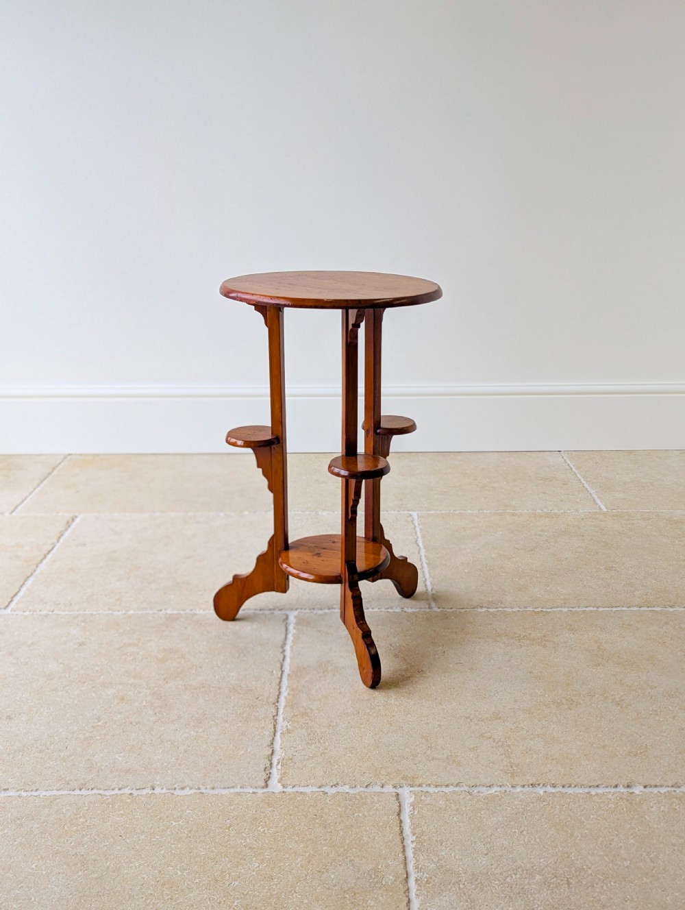 An early 20th-century stained beech occasional table featuring a circular top, three small side tiers, a lower circular shelf, and curved bracket feet. View IX