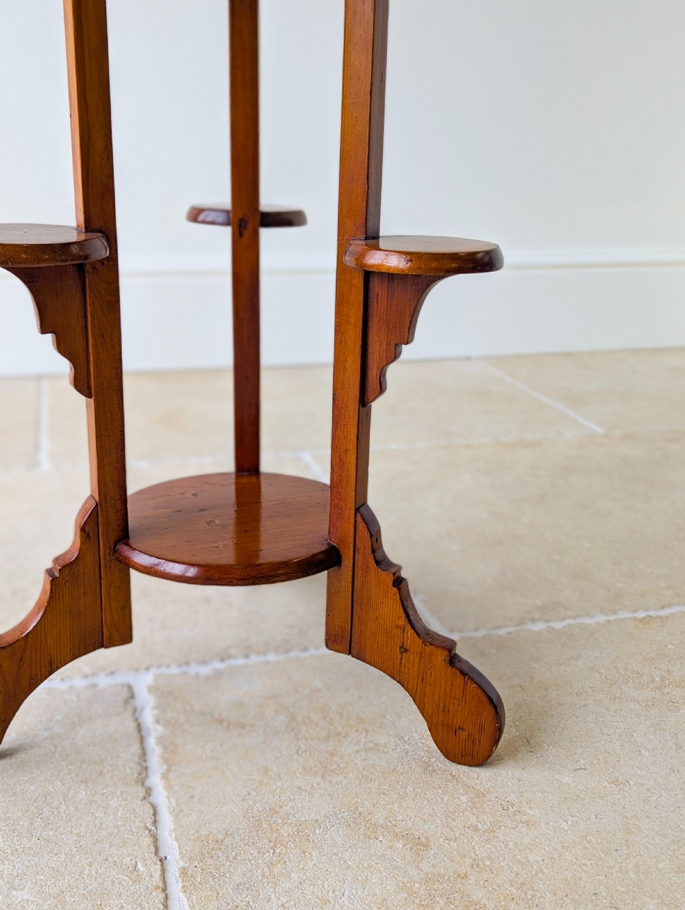 An early 20th-century stained beech occasional table featuring a circular top, three small side tiers, a lower circular shelf, and curved bracket feet. View X