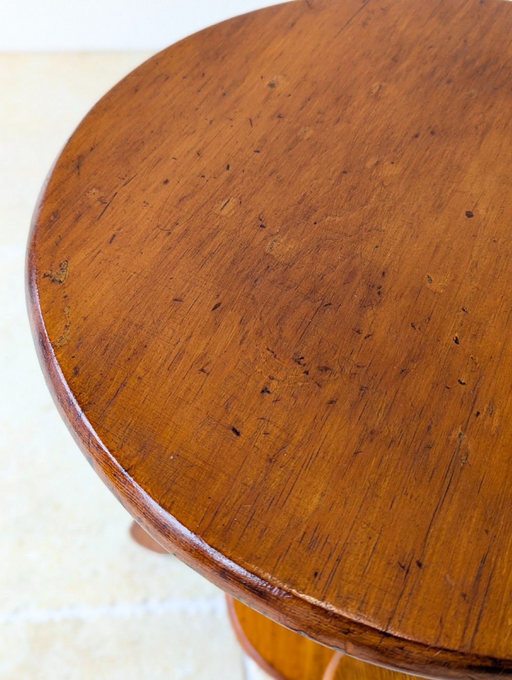 An early 20th-century stained beech occasional table featuring a circular top, three small side tiers, a lower circular shelf, and curved bracket feet. View XIII