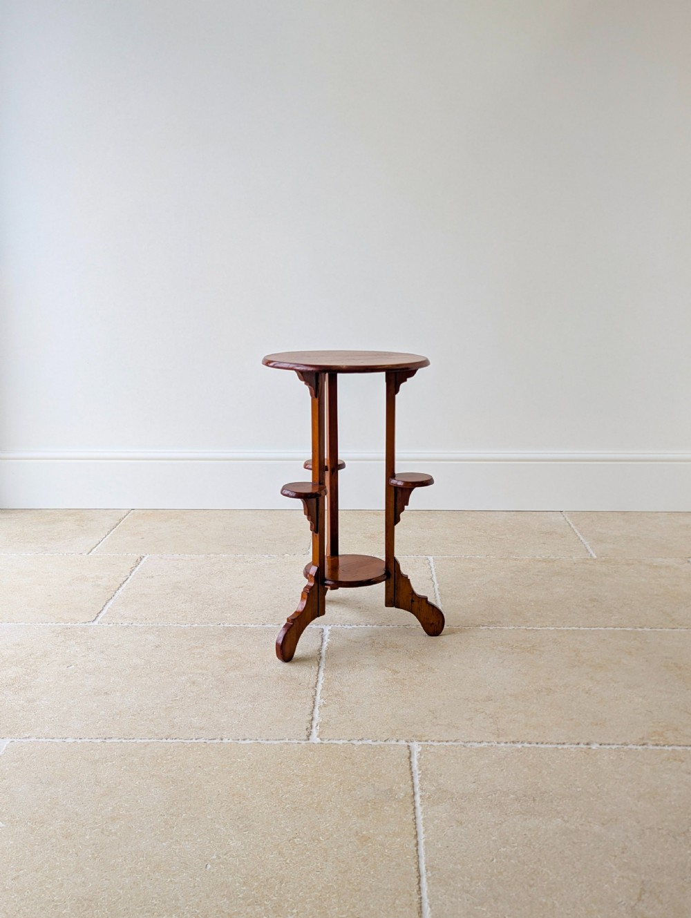 An early 20th-century stained beech occasional table featuring a circular top, three small side tiers, a lower circular shelf, and curved bracket feet. View XIV