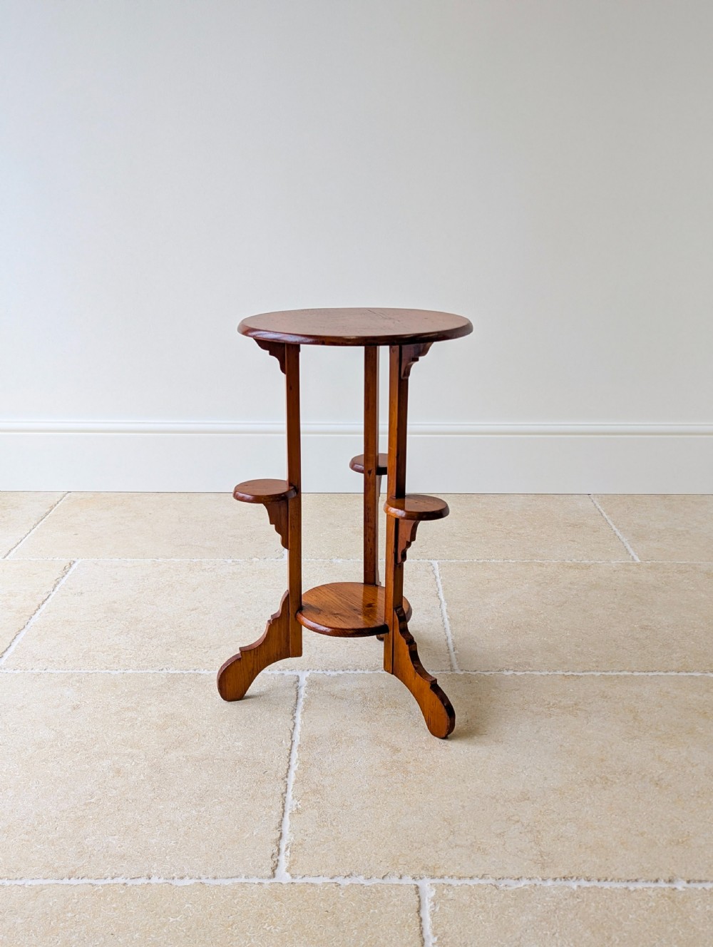 An early 20th-century stained beech occasional table featuring a circular top, three small side tiers, a lower circular shelf, and curved bracket feet. View XVI