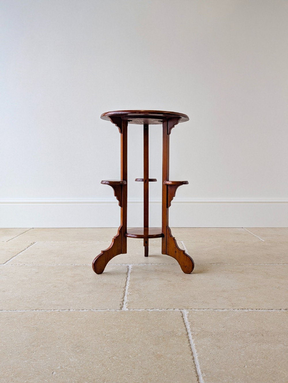 An early 20th-century stained beech occasional table featuring a circular top, three small side tiers, a lower circular shelf, and curved bracket feet. View XVII