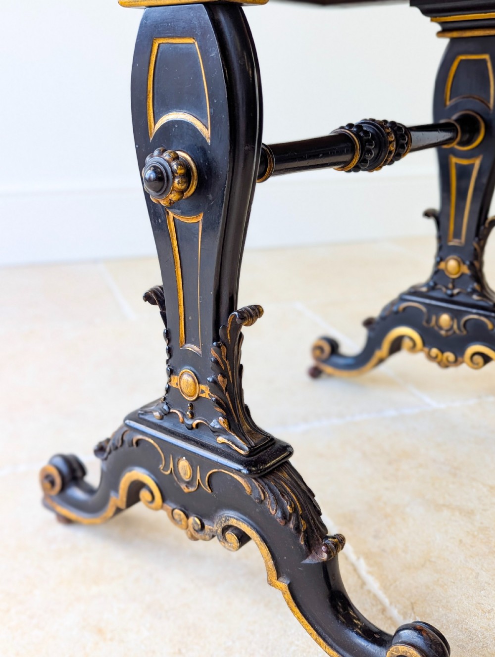 A Victorian ebonised bonheur du jour writing desk featuring gilded accents, a raised superstructure with small drawers, a brass gallery rail, and turned stretcher support. View V