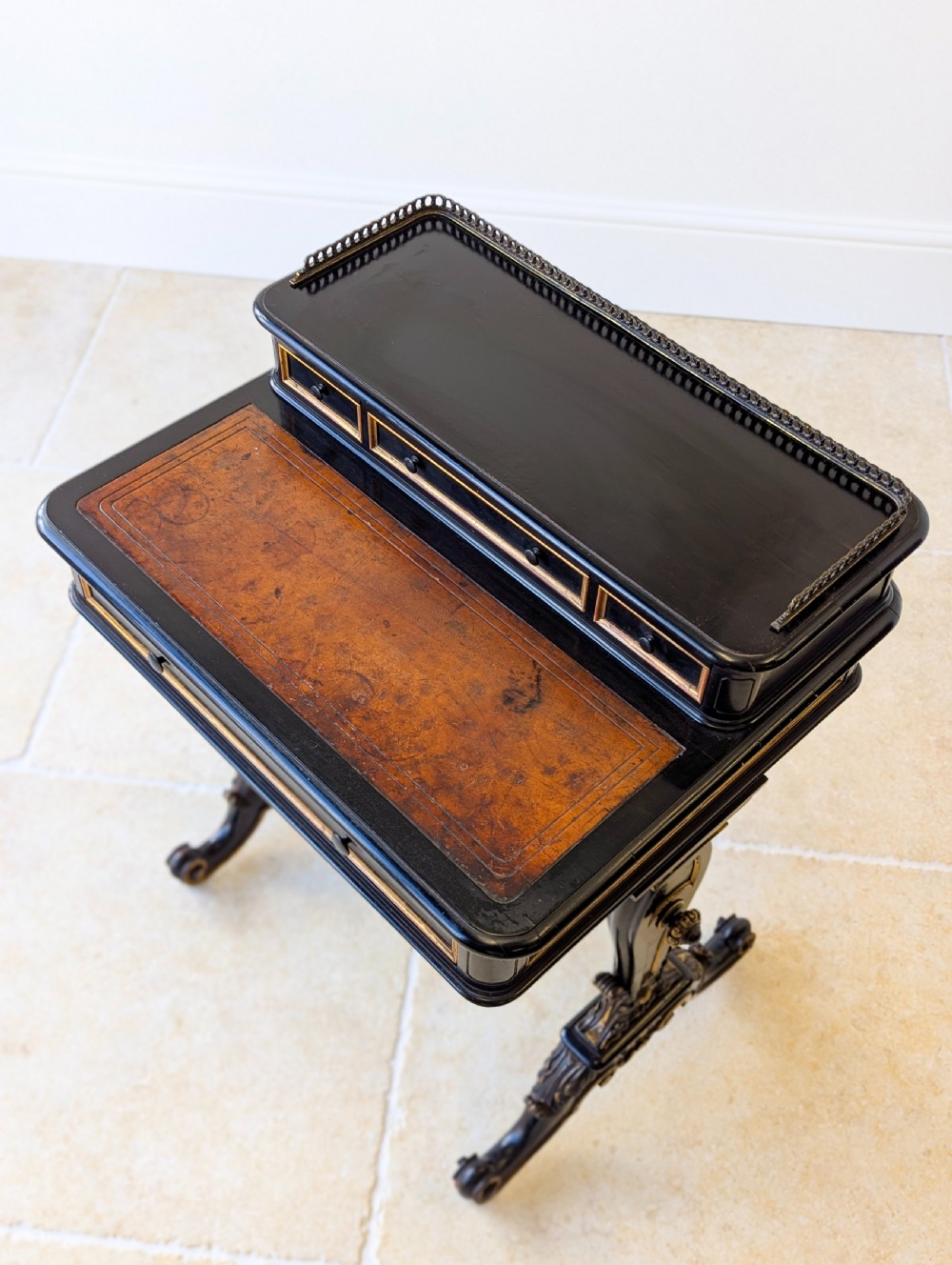 A Victorian ebonised bonheur du jour writing desk featuring gilded accents, a raised superstructure with small drawers, a brass gallery rail, and turned stretcher support. View XI
