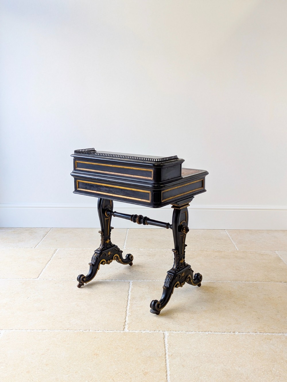 A Victorian ebonised bonheur du jour writing desk featuring gilded accents, a raised superstructure with small drawers, a brass gallery rail, and turned stretcher support. View XVI