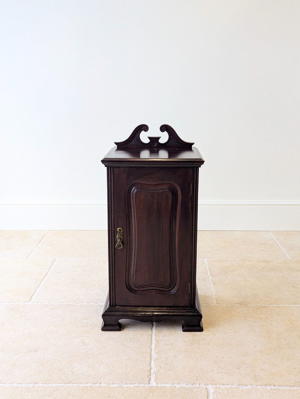 An antique Victorian dark mahogany bedside cabinet with a carved gallery back, a single door with a molded panel, and a sturdy plinth base. View II