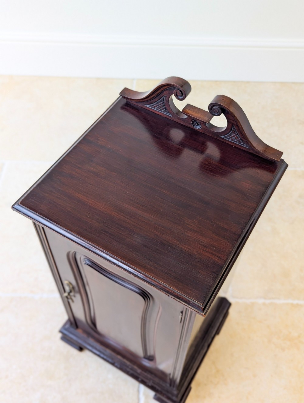 An antique Victorian dark mahogany bedside cabinet with a carved gallery back, a single door with a molded panel, and a sturdy plinth base. View III