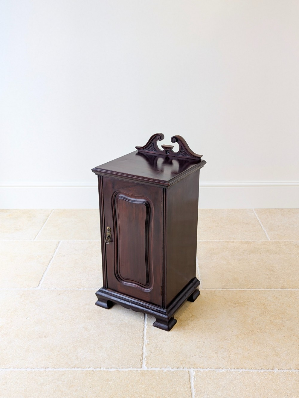 An antique Victorian dark mahogany bedside cabinet with a carved gallery back, a single door with a molded panel, and a sturdy plinth base. View IV