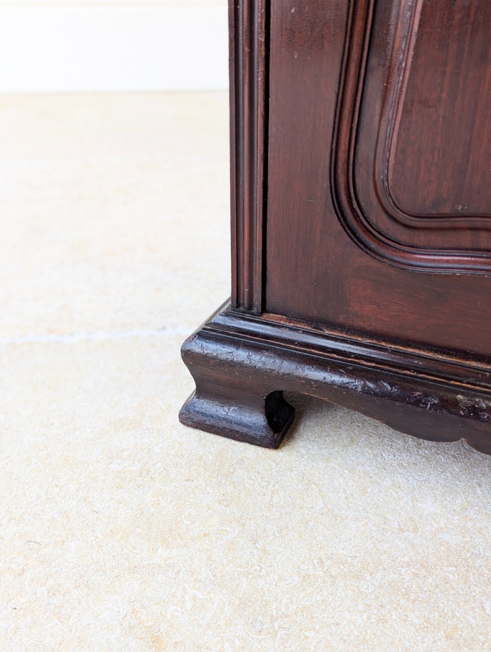 An antique Victorian dark mahogany bedside cabinet with a carved gallery back, a single door with a molded panel, and a sturdy plinth base. View V