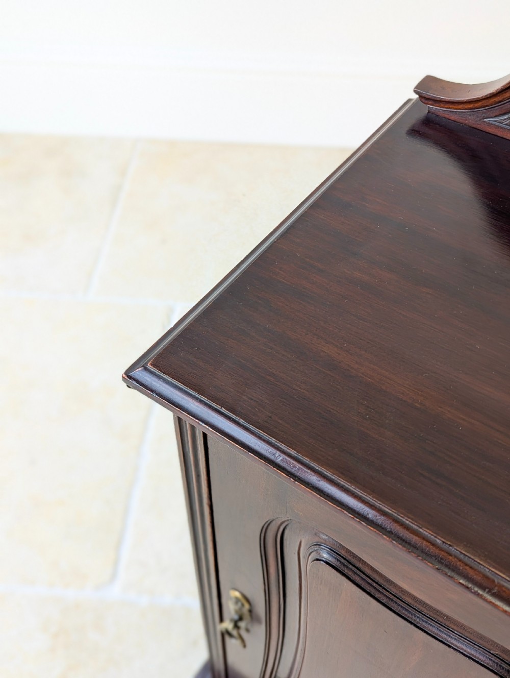An antique Victorian dark mahogany bedside cabinet with a carved gallery back, a single door with a molded panel, and a sturdy plinth base. View VII