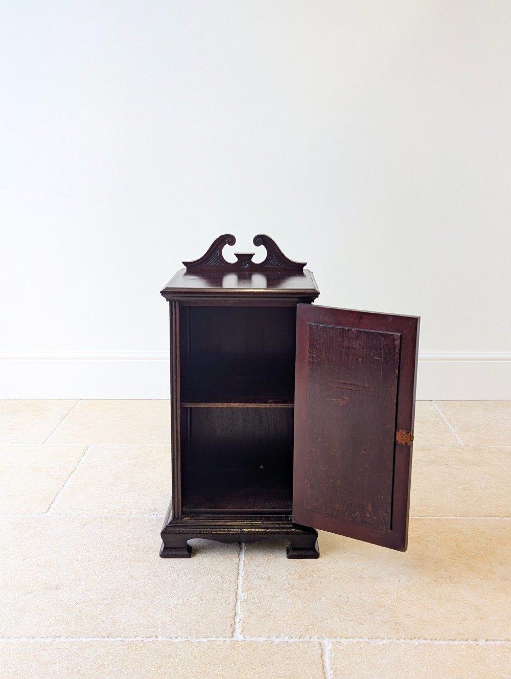 An antique Victorian dark mahogany bedside cabinet with a carved gallery back, a single door with a molded panel, and a sturdy plinth base. View VIII