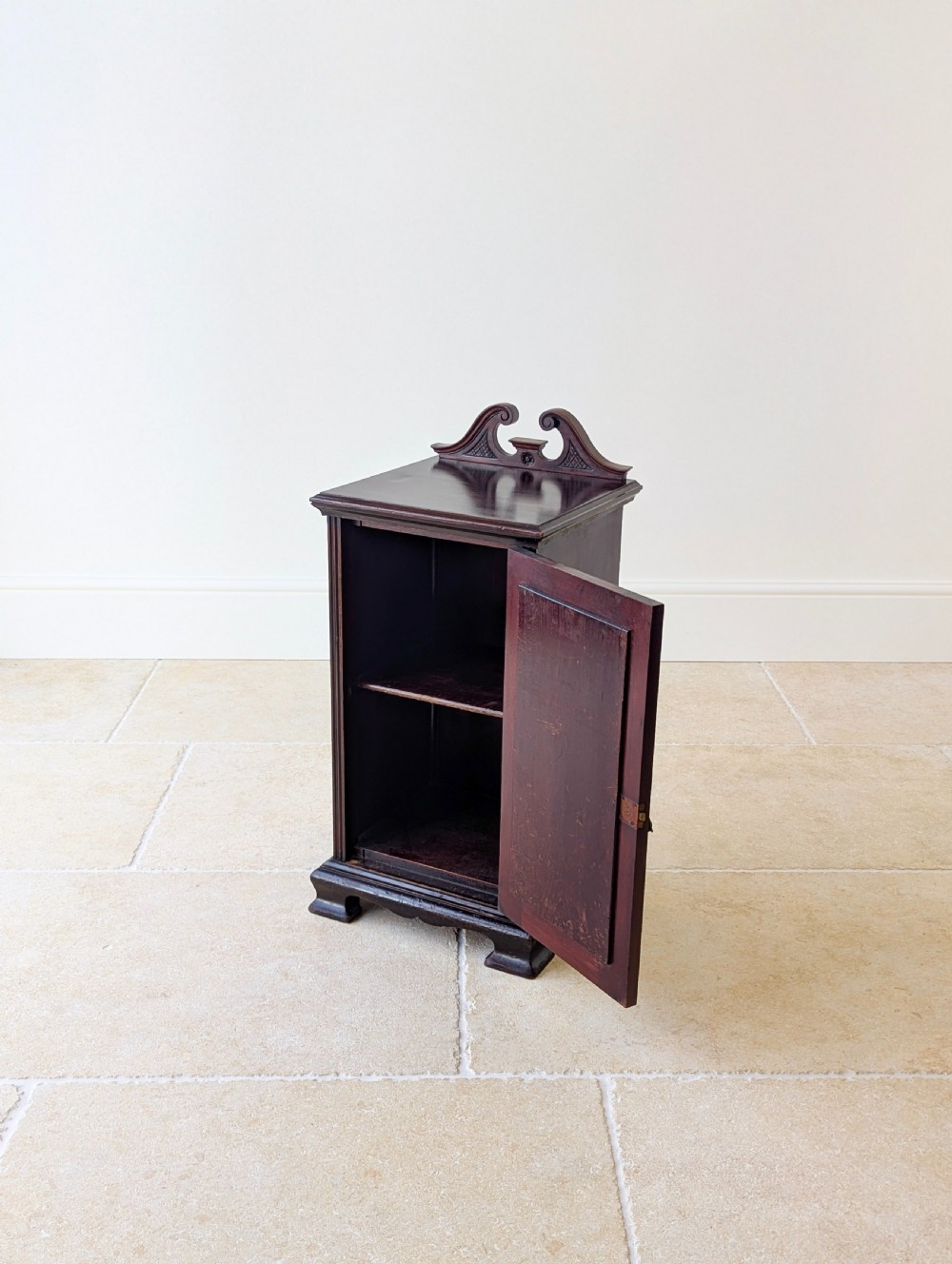 An antique Victorian dark mahogany bedside cabinet with a carved gallery back, a single door with a molded panel, and a sturdy plinth base. View X