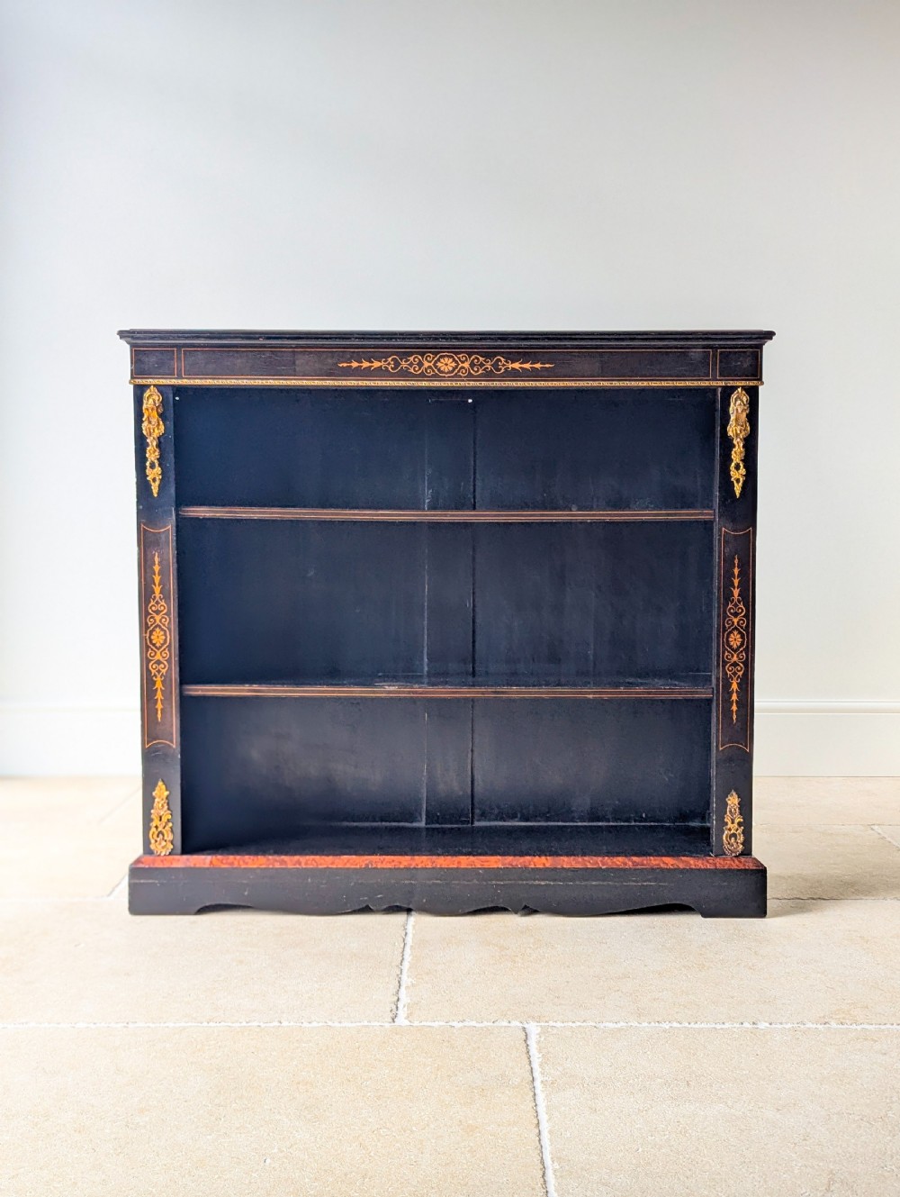 A Victorian ebonised open bookcase with three shelves, gold inlay, and gilt bronze mounts along the side uprights. View II