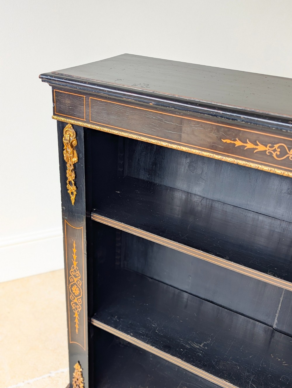 A Victorian ebonised open bookcase with three shelves, gold inlay, and gilt bronze mounts along the side uprights. View III