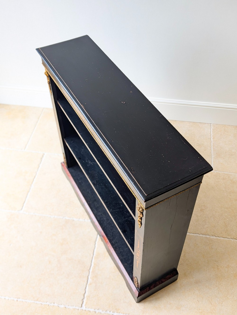 A Victorian ebonised open bookcase with three shelves, gold inlay, and gilt bronze mounts along the side uprights. View IV