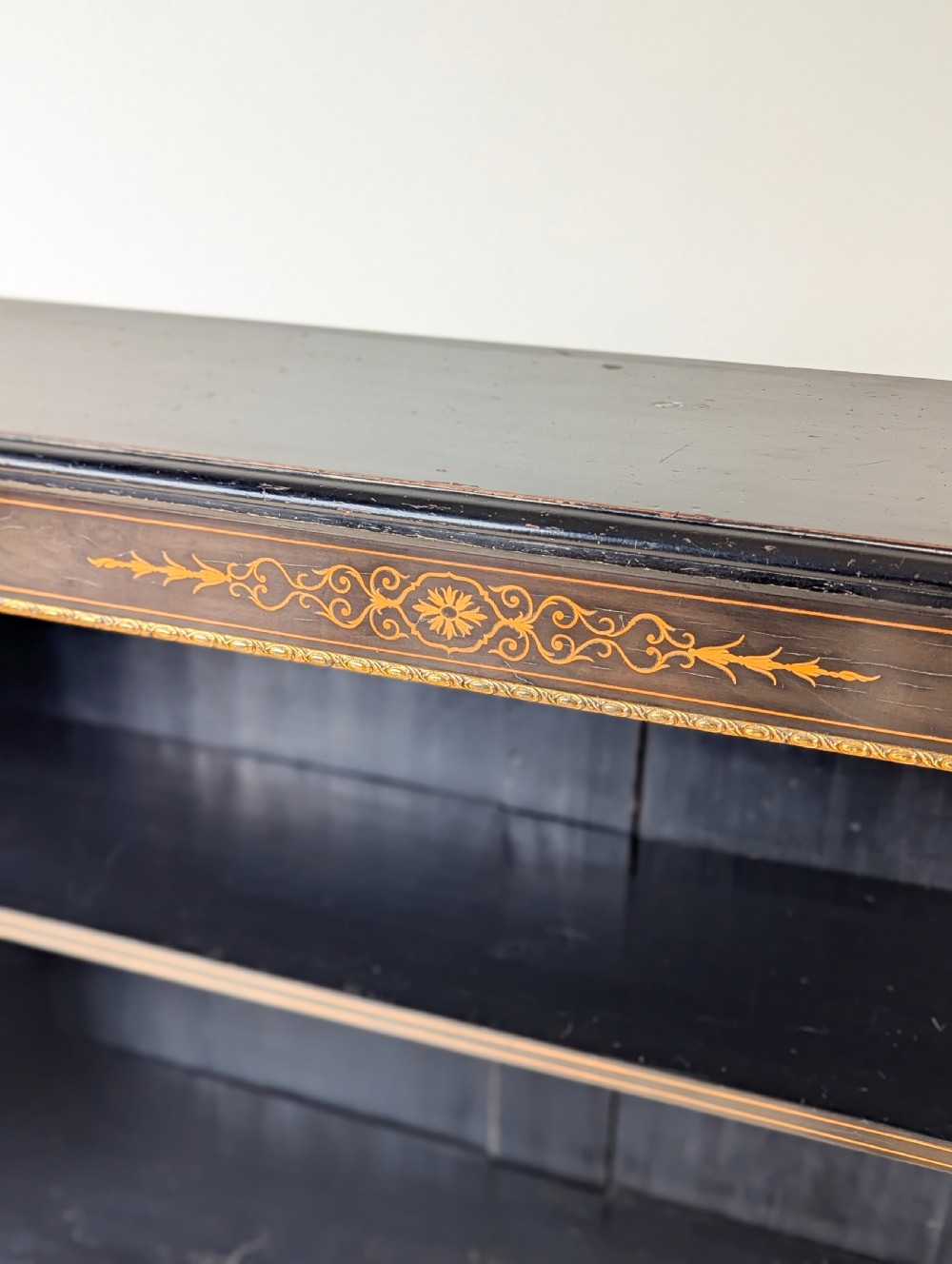 A Victorian ebonised open bookcase with three shelves, gold inlay, and gilt bronze mounts along the side uprights. View VI