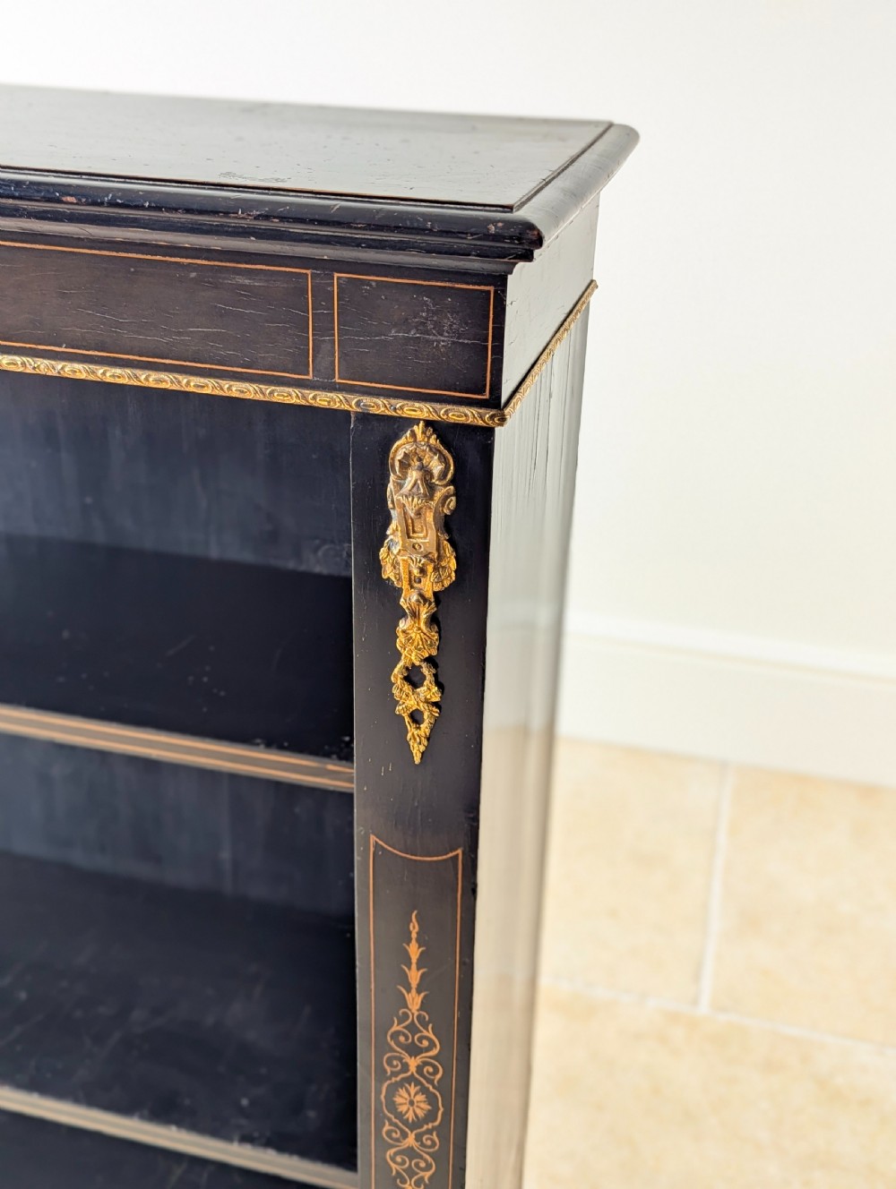 A Victorian ebonised open bookcase with three shelves, gold inlay, and gilt bronze mounts along the side uprights. View VIII